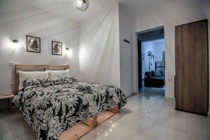 A bedroom with a bed, bedside tables, and a wooden wardrobe. - Terra di Meteora Suites #3 (Kalampaka)
