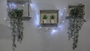 Three wall-mounted light fixtures with hanging plants, each containing two potted plants. - Terra di Meteora Suites #3 (Kalampaka)