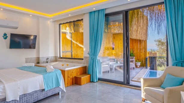 Une chambre d’hôtel moderne dotée d’un grand lit, d’une salle de bain séparée, d’un balcon avec vue et d’un téléviseur fixé au mur.
