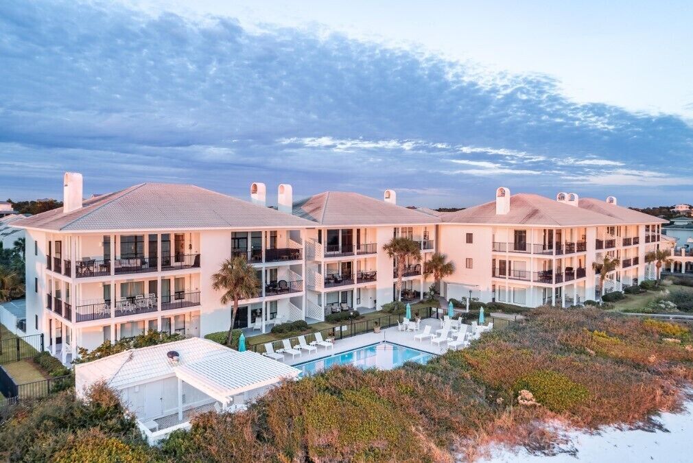 Ein mehrstöckiges Hotel mit Balkonen, einem Schwimmbad und Blick auf den Strand.