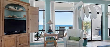 A spacious living room with a television, wooden cabinet, and a glass coffee table.