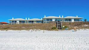 A beachfront property with multiple white buildings, a staircase leading up to the beach, and a clear blue sky. - Gulf Front, Gorgeous Views, Top Floor, Pool, Gated Complex, 30A (Santa Rosa Beach)