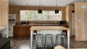 Una cocina moderna con armarios de madera, una isla grande con taburetes de bar e iluminación colgante.