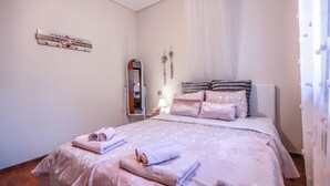Une chambre à coucher avec un lit, des oreillers, une table de chevet, un miroir et un élément de décoration murale.