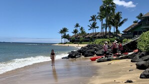 A beach with a clear sky, a person walking, and a red kayak on the sand. - Spectacular, fully renovated 3-Bedroom Oceanfront Townhome in Kahana (Lahaina)