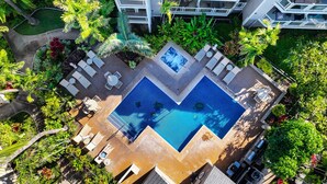 An aerial view of a hotel with a central swimming pool, outdoor seating, and lush greenery. - 2BR/2BA Wailea Condo w AC Pool Close to Beach - Grand Champions 163 (Kihei)