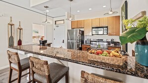 A modern kitchen with granite countertops, stainless steel appliances, and a central island with bar stools. - 2BR/2BA Wailea Condo w AC Pool Close to Beach - Grand Champions 163 (Kihei)