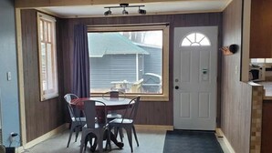 A compact living space with a dining area, a door, and a small kitchenette. - Sturgeon Cabin - Fremont, WI (Fremont)