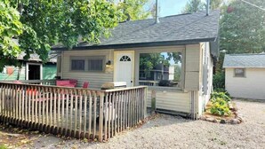 A small, single-story building with a porch and a fenced area. - Sturgeon Cabin - Fremont, WI (Fremont)