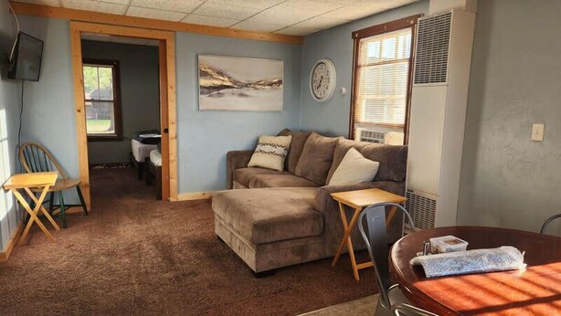 A cozy living room with a sofa, a small table, and a TV. - Sturgeon Cabin - Fremont, WI (Fremont)