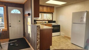 A compact kitchen with wooden cabinets, a built-in oven, and a refrigerator. - Sturgeon Cabin - Fremont, WI (Fremont)