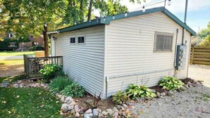 A small, single-story mobile home with a gabled roof, a front porch, and a small attached garage. - Crappie Cabin - Fremont, WI (Fremont)