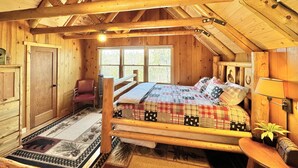 Una camera da letto accogliente con un letto di legno, una sedia, una scrivania e una finestra.