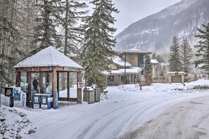 Ett snötäckt utomhusområde med en träkonstruktion, eventuellt ett kiosk eller en informationsstuga, och en byggnad i bakgrunden.