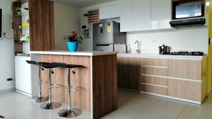 A modern kitchen with a central island, bar stools, a built-in oven, and a microwave. - La Martinera Avenida San José (Guatapé)