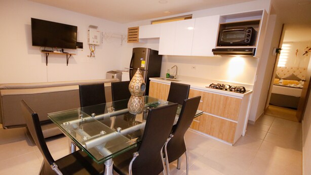 Una cocina moderna con una mesa de comedor de vidrio, sillas negras, un microondas y un horno empotrado.