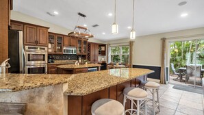 A spacious kitchen with granite countertops, stainless steel appliances, and a large island with bar stools. - Double oven | Volleyball Net | 4 Famous Beaches | 1 Level (Sarasota)