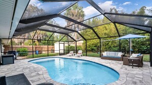 A covered outdoor swimming pool with a curved design, surrounded by a patio area with seating and a table. - Double oven | Volleyball Net | 4 Famous Beaches | 1 Level (Sarasota)