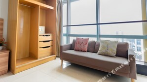 A modern living room with a wooden wardrobe, a sofa with cushions, and a large window offering a city view. - Sunny Private Apt of Grand Continental (Guangzhou)