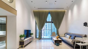 A modern living room with a sofa, TV, and a large window with curtains. - Sunny Private Apt of Grand Continental (Guangzhou)