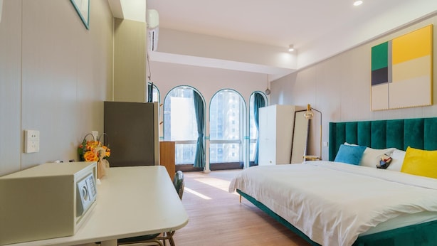 A modern bedroom with a bed, a desk, and a window with curtains. - Sunny Private Apt of Grand Continental (Guangzhou)