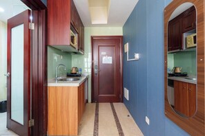 A compact kitchen with wooden cabinets, a built-in microwave, and a small countertop.