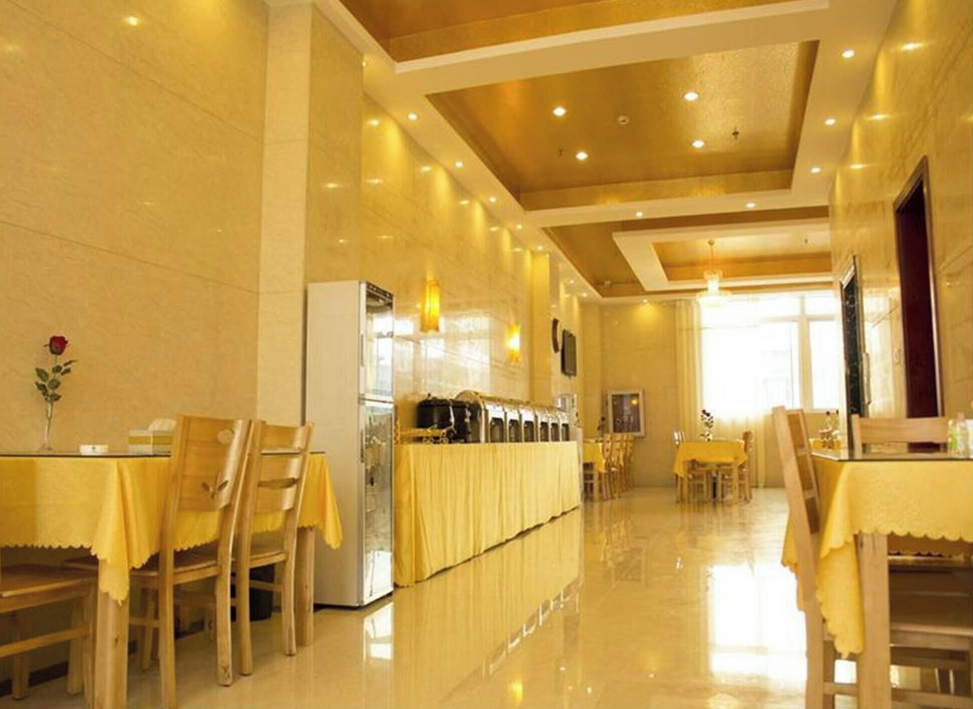 A hotel dining area with wooden chairs and tables, a buffet counter, and a modern ceiling design.