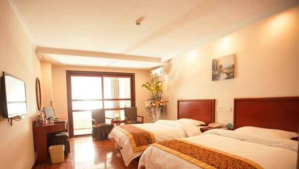 A hotel room with two beds, a desk, a chair, a TV, and a large window. - Greentree Inn Lianyungang Guanyun Bus Station Zhenxing Garden Express (Lianyungang)