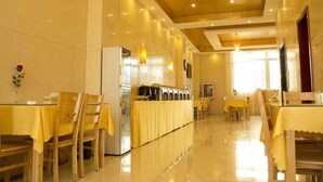 A hotel dining area with tables and chairs, a refrigerator, and a buffet setup. - Greentree Inn Lianyungang Guanyun Bus Station Zhenxing Garden Express (Lianyungang)