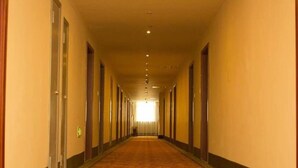 A long, narrow hallway with doors on both sides, carpeted floor, and a light at the end. - Greentree Inn Lianyungang Guanyun Bus Station Zhenxing Garden Express (Lianyungang)