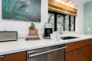 Cozinha moderna com cafeteira, livros e um cacto no balcão.