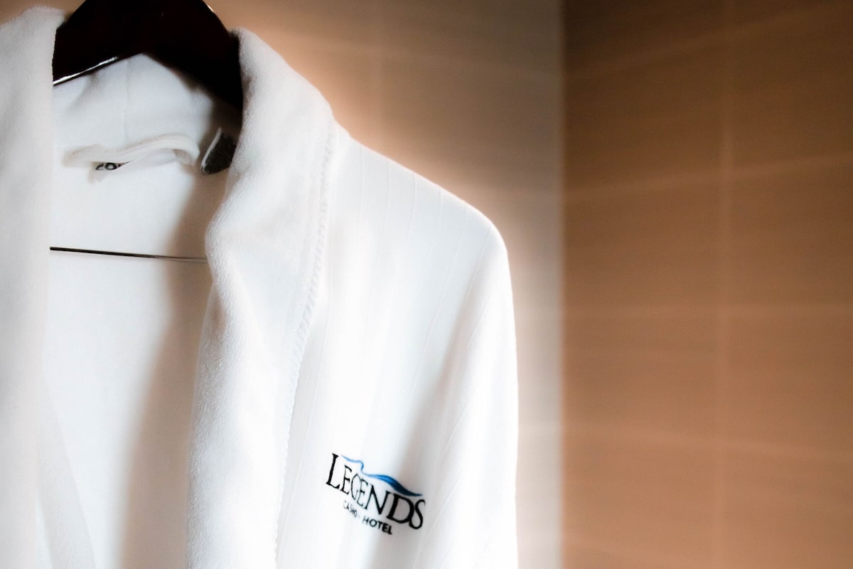 A white robe hanging on a hanger in a bathroom with a marble countertop and a sink.