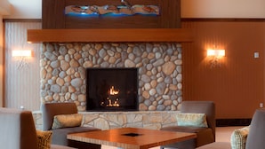 A stone fireplace with a fire, surrounded by seating and a wooden table. - Legends Casino Hotel (Toppenish)