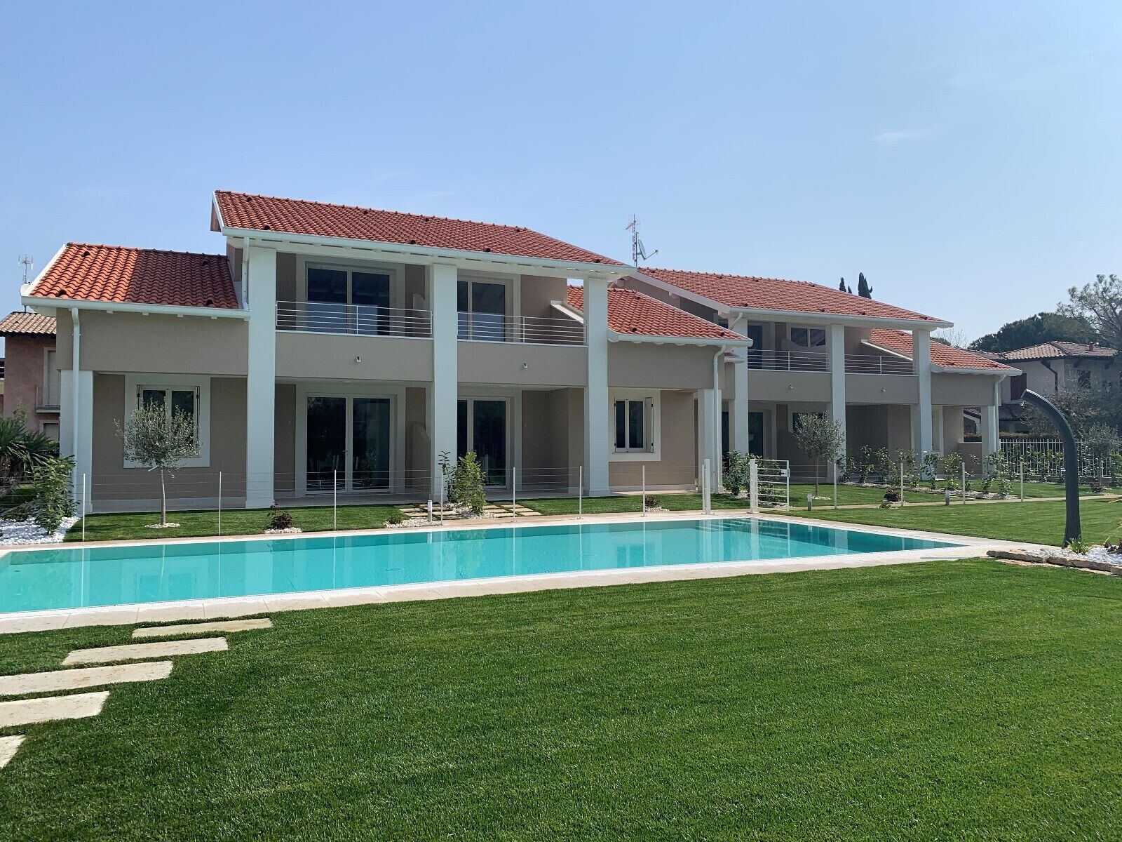 A two-story house with a swimming pool in front.