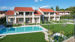 Ein modernes Hotel mit Pool, mehreren Balkonen und einem gepflegten Rasen.