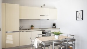 Cozinha compacta com área de refeições, com máquina de café, pia e um vaso de planta.