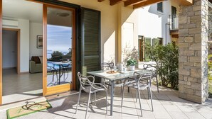 Um pátio com mesa e cadeiras, vista para uma piscina e um muro de pedra.