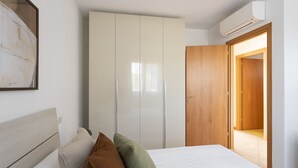 Um quarto com uma cama, um guarda-roupa, uma porta de madeira e um aparelho de ar condicionado.