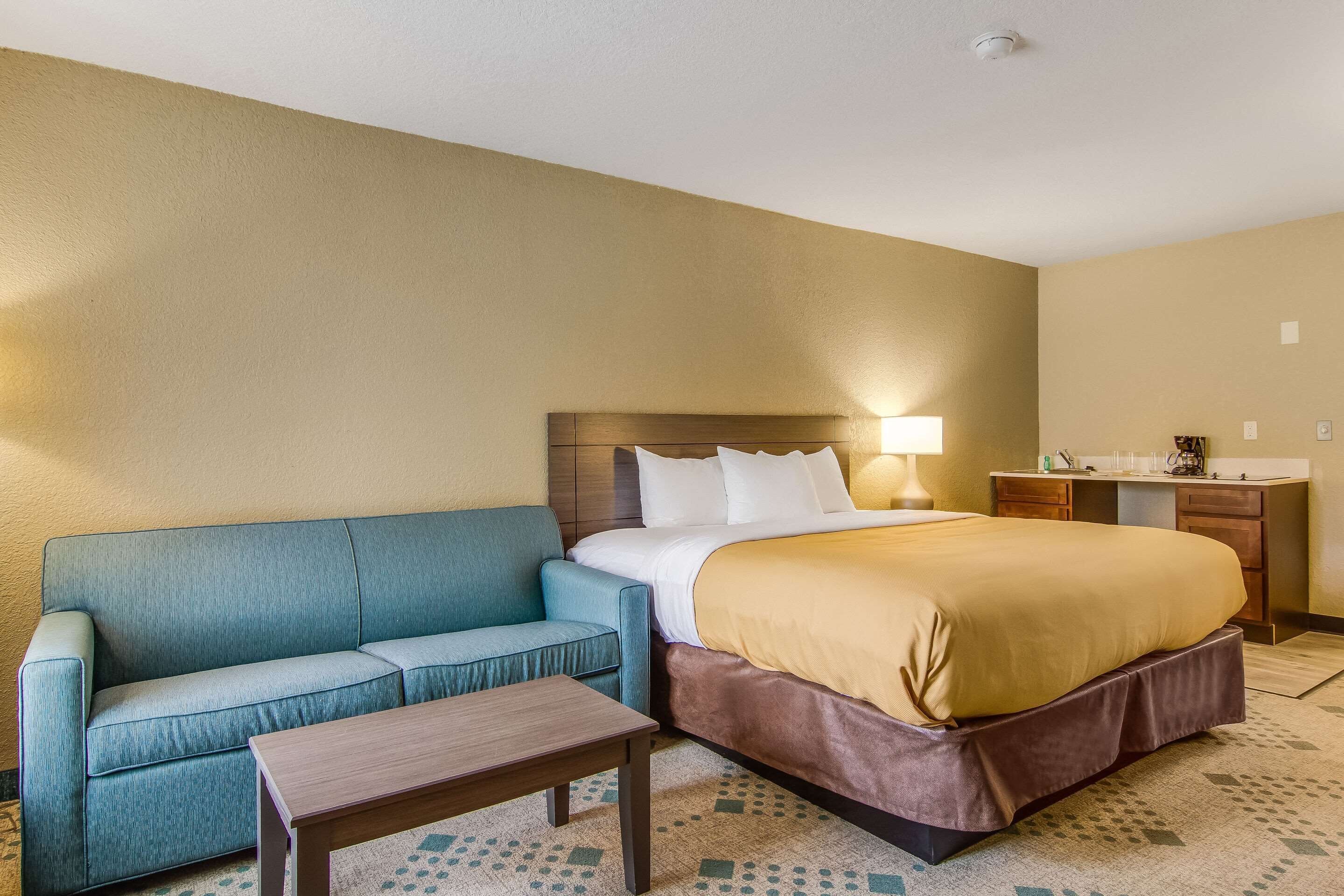 Una habitación de hotel con cama, sofá, escritorio y lámpara.