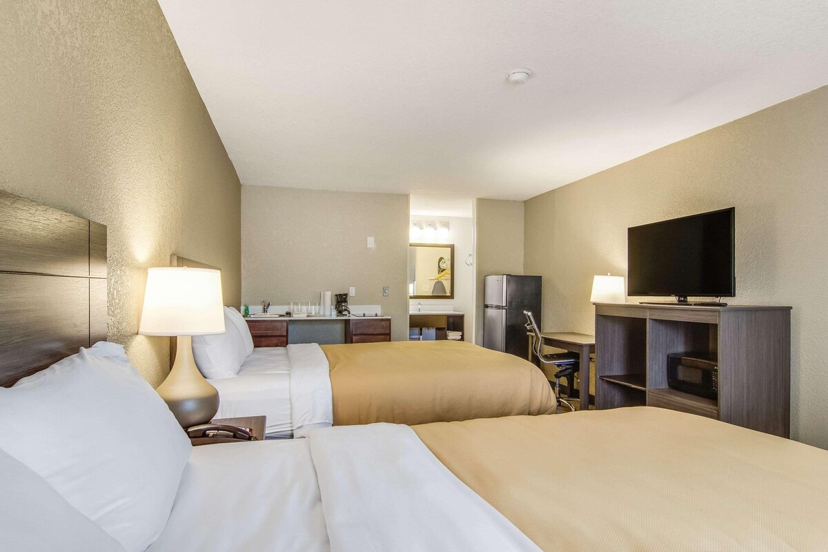 Een hotelkamer met twee bedden, een bureau, een televisie en een magnetron.