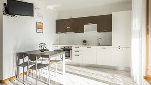 Eine moderne Küche mit weißen Schränken, einem eingebauten Ofen und einem Essbereich mit Tisch und Stühlen.