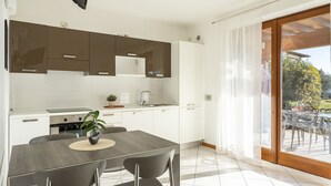 Eine moderne Küche mit weißen Schränken, einem eingebauten Backofen und einem Essbereich mit Tisch und Stühlen.