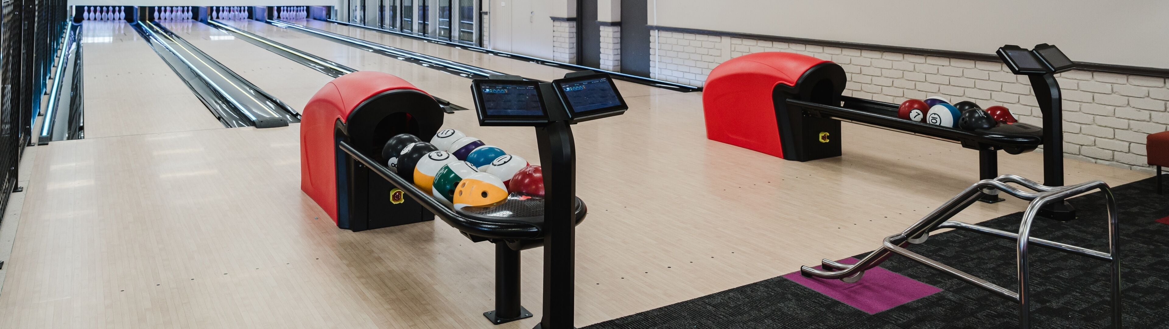 Bolera con pistas, un sistema de devolución de pelotas de bolos y una mesa de billar.