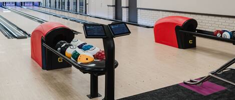 Bolera con pistas, un sistema de devolución de pelotas de bolos y una mesa de billar.