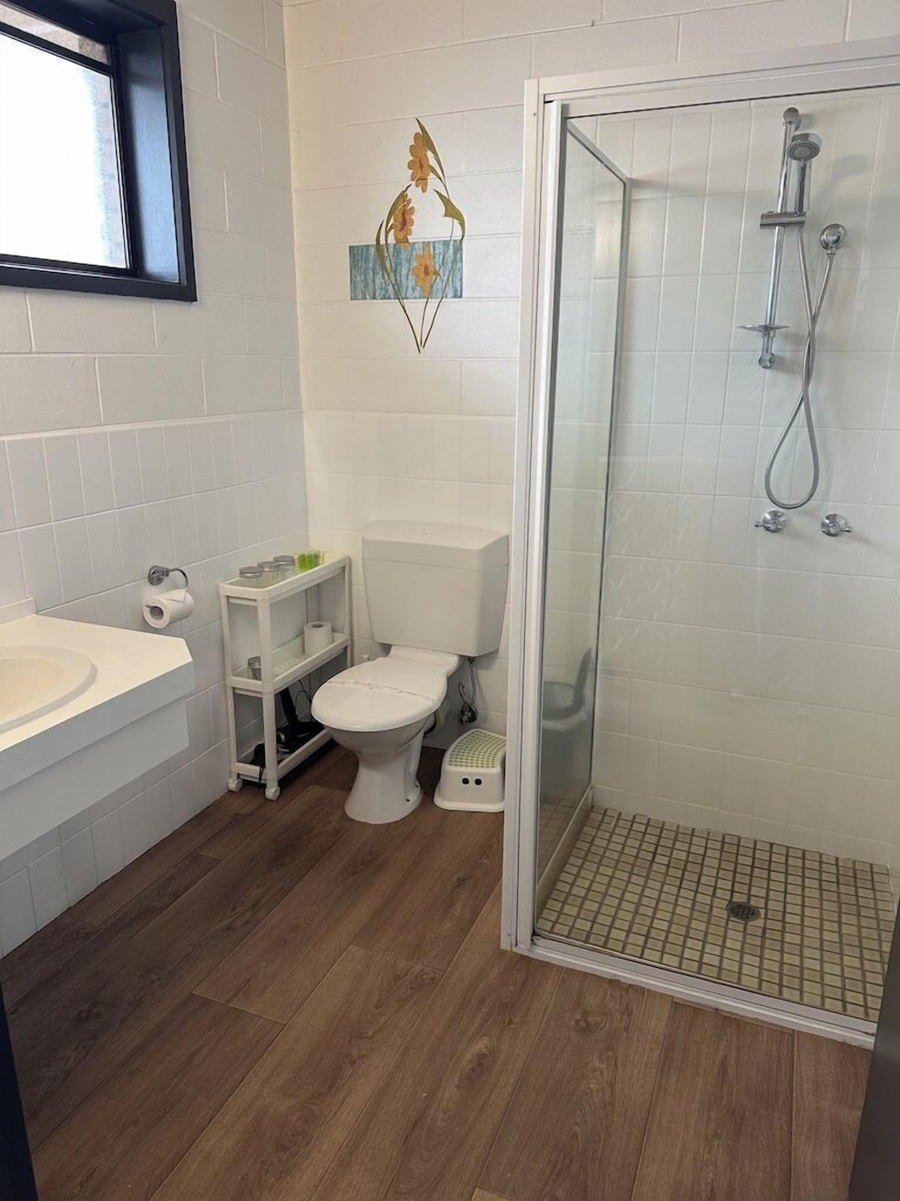 Une salle de bain équipée d’une douche, de toilettes, d’un lavabo et d’un élément décoratif mural.