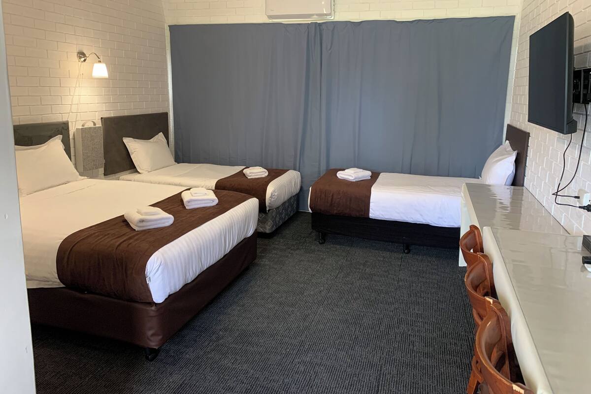A hotel room with two beds, a desk, and a TV.