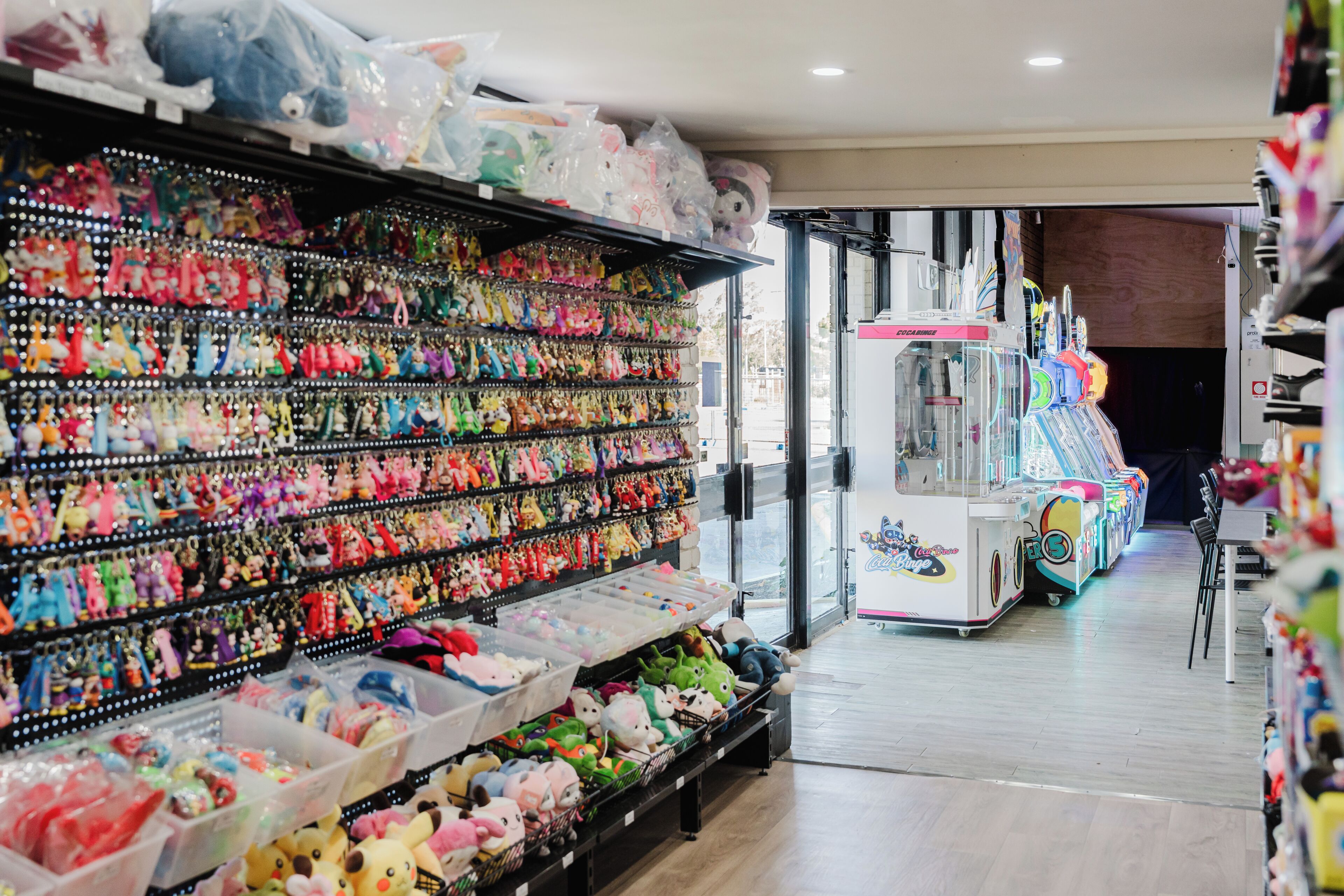 A vending area with various gaming machines and shelves stocked with plush toys.