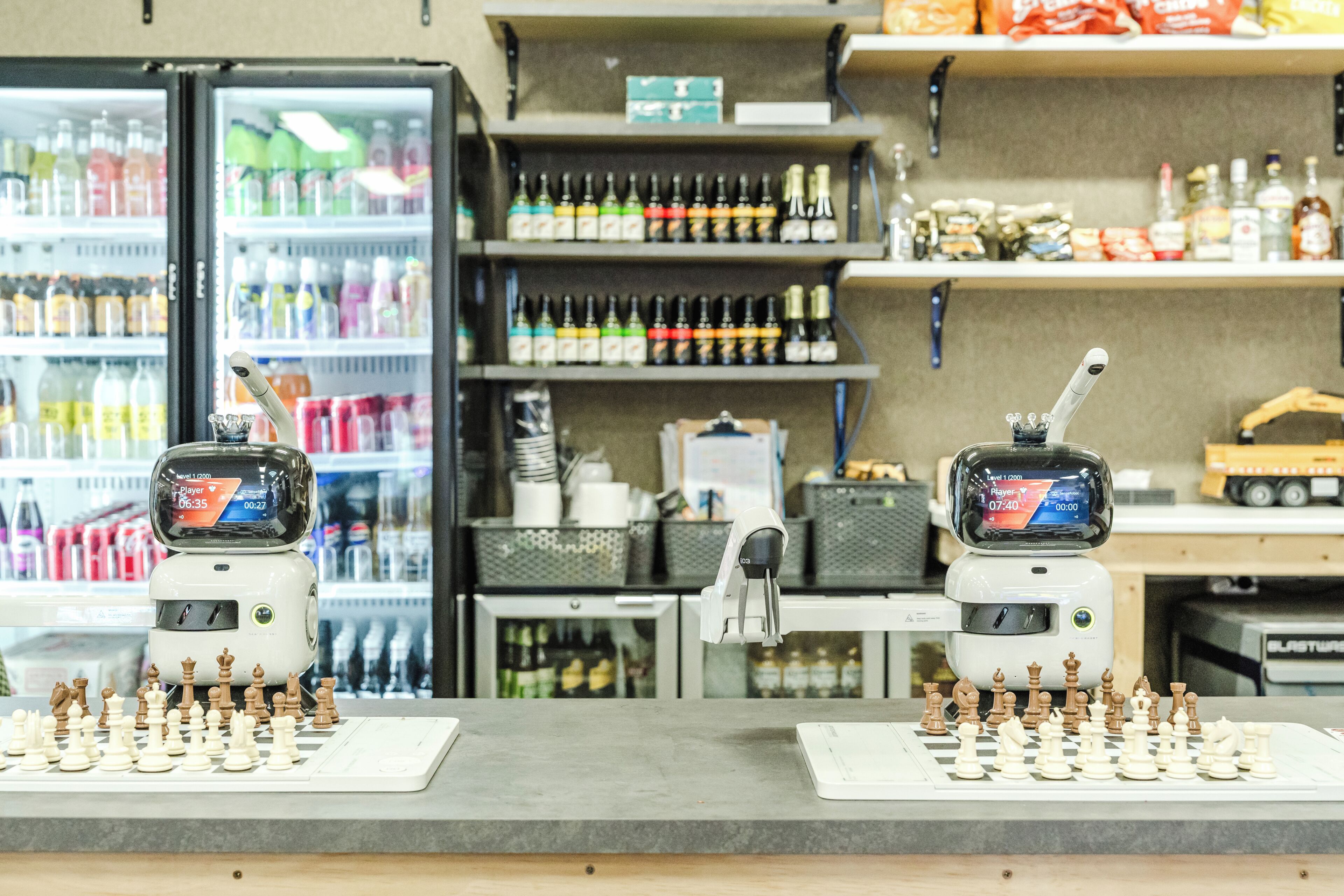 Un tablero de ajedrez sobre una encimera, con un refrigerador de bebidas y estantes llenos de botellas al fondo.