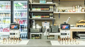 Un tablero de ajedrez sobre una encimera, con un refrigerador de bebidas y estantes llenos de botellas al fondo.