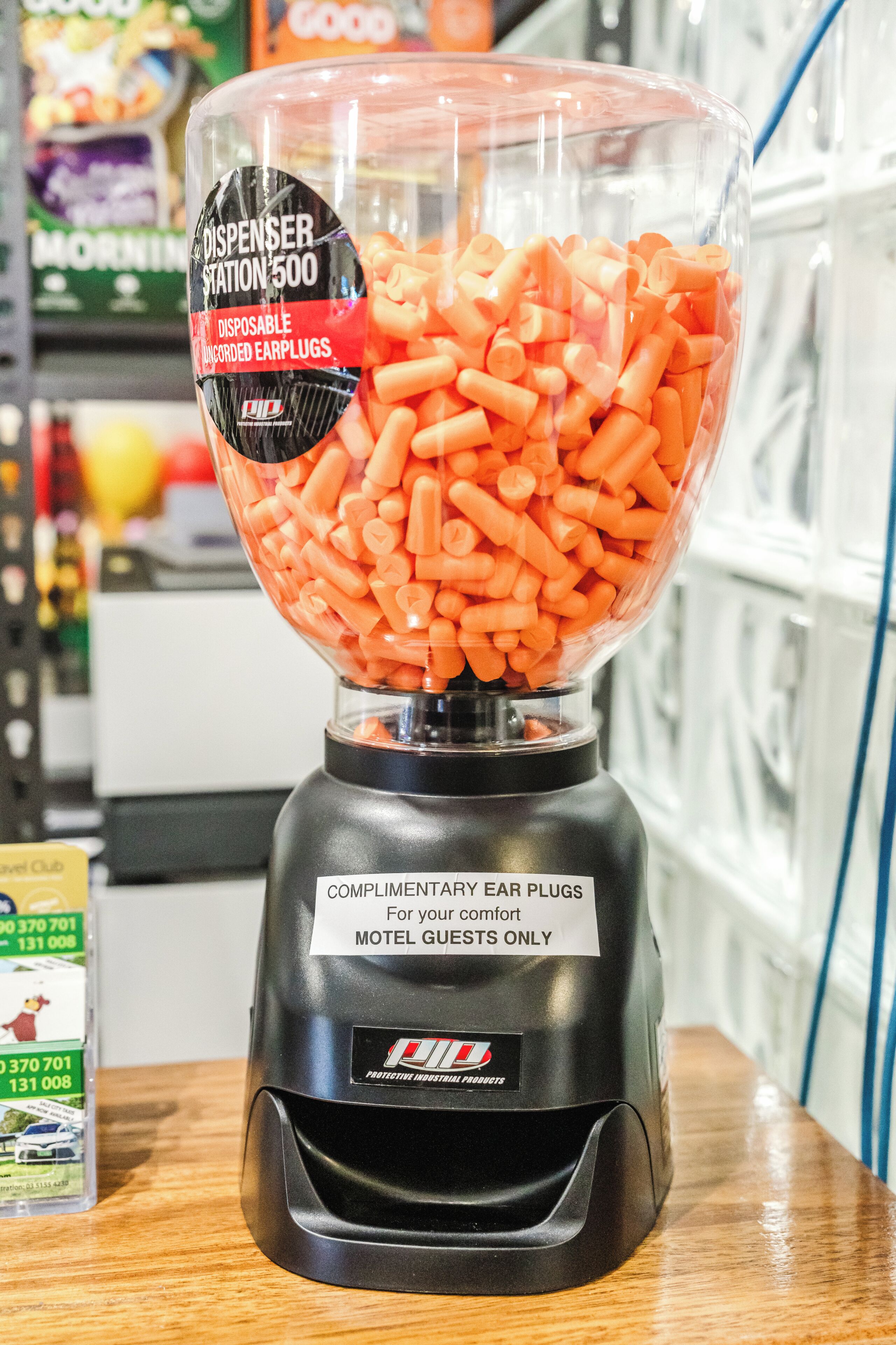 A black blender filled with orange items, labeled for motel guests, in a store setting.